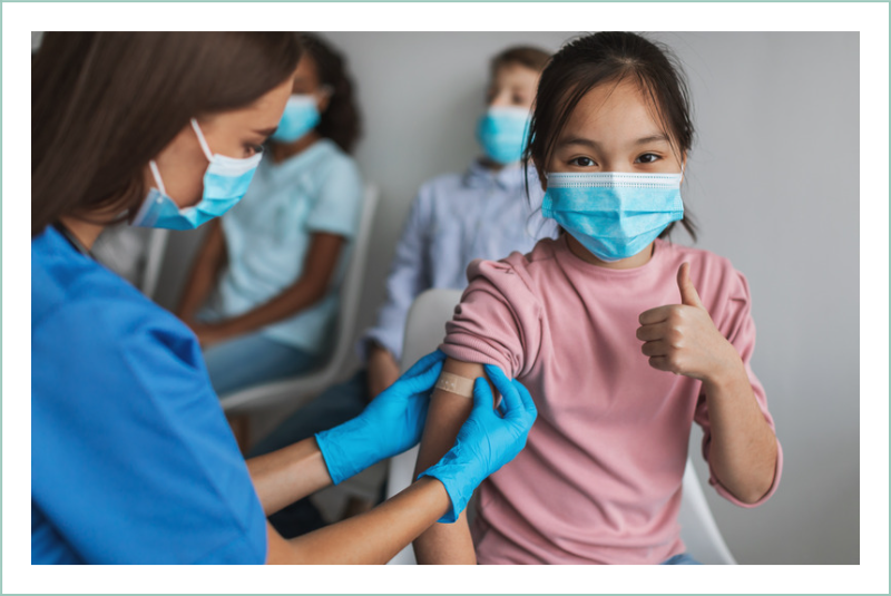 Young girl giving a thumbs up while receiving a vaccination