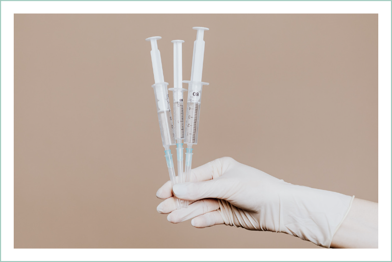 Gloved hand holding three syringes