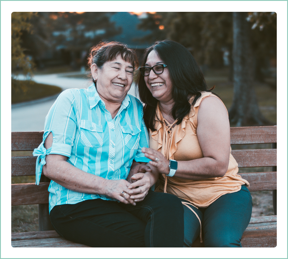 middle aged daughter and mother sitting on a park bench